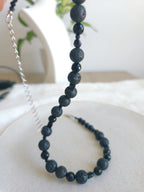 Black beaded necklace on a white surface with a blurred background